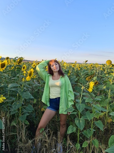 Young woman standing in blooming sunflower field under blue sky