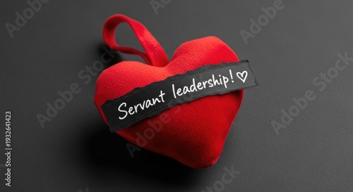 Red fabric heart ornament with servant leadership ribbon label, dark minimalist backdrop, servant leadership concept