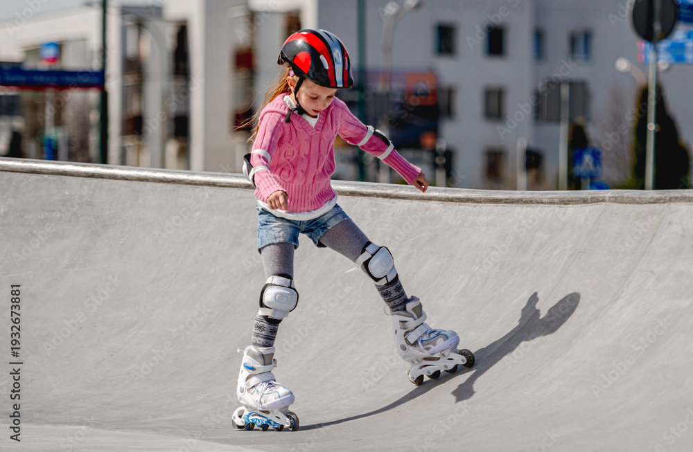 Fototapeta premium Little Girl Roller Skating In A Helmet At The Skatepark In Spring