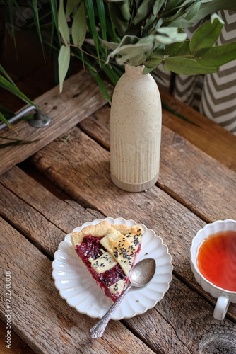 Side view of a cherry pie slice with black sesame and a cup of tea