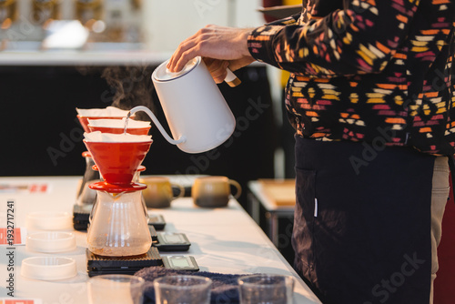 Photography Professional barista brewing craft filter coffee using a white gooseneck kettle and red ceramic drippers on digital scales