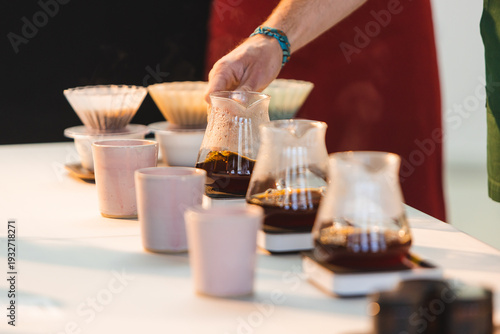 Schilderij op canvas Professional barista hand lifting a glass carafe during a specialty coffee cupping and pour-over tasting session