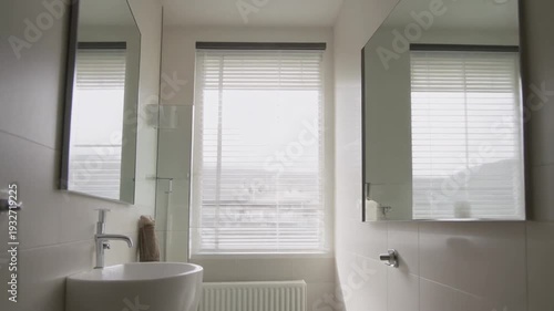Modern bathroom interior with sink, mirror, and window, viewed from the side, showcasing clean lines and minimalist decor