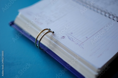 Open Notebook with Handwritten Notes and Gold Spiral Binding on Blue Background