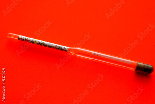 Принти на полотні A glass hydrometer for measuring alcohol strength is placed horizontally on a rich red background