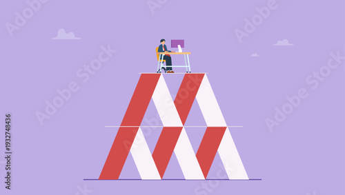 Businessman working on a desk on a house of cards depicting instability and risk.