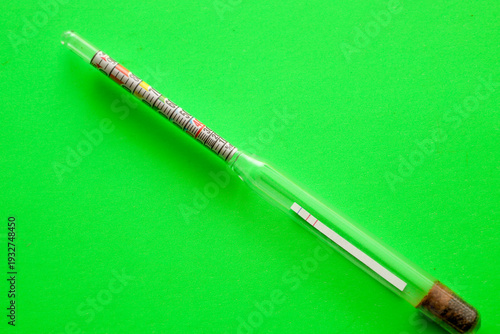 Photos A glass household alcoholometer is placed diagonally on a vivid light green background