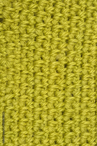 A detailed top view of a lime green handmade crochet fabric with a repeating textured stitch pattern made of soft wool yarn