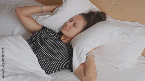 Unsettled visitor battles noise using makeshift clothing tools for relief. Restless guest struggles with disturbances and noise while attempting to sleep peacefully using improvised items