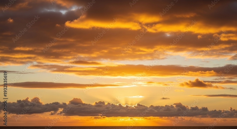 Fototapeta premium A vibrant sunset paints the sky with warm hues, sunlight bursting through the clouds over water