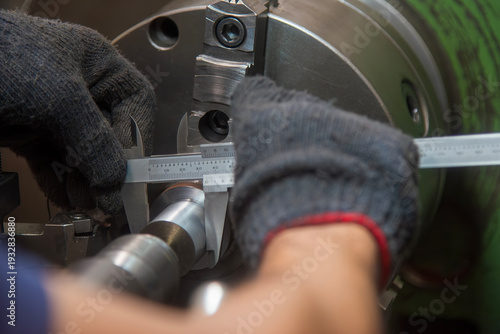 Canvastavla In-process dimensional inspection of a machined metal shaft using a vernier caliper by a skilled machine operator on a lathe