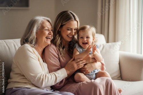 Three generations of women laughing together on a sofa at home.