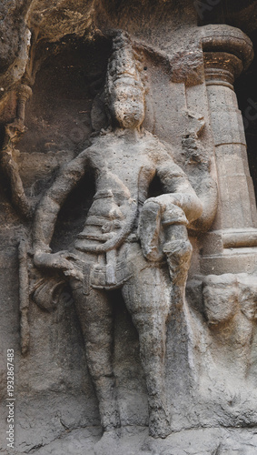 Monolithic standing guardian statue carved in basalt rock at Kailasa Temple, Ellora Caves.