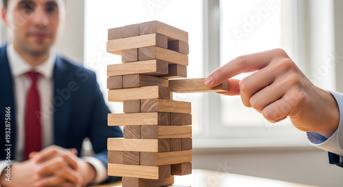 Businessman playing Jenga game with hand stacking wooden blocks in office environment carefully