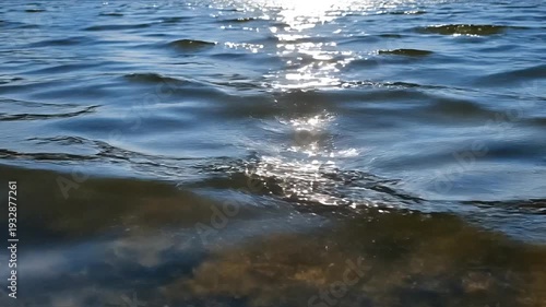 Closeup of gentle blue water waves with sparkling sunlight reflections creating a serene and calming natural background for relaxation and meditation.