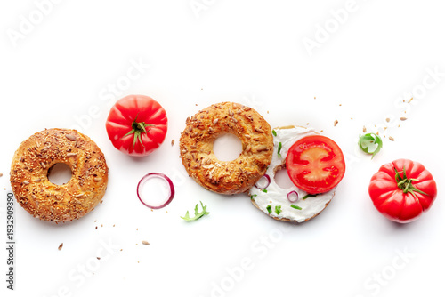 Vegetarian bagel panorama, healthy bread with tomato and onion, shot from the top on a white background, with copy space