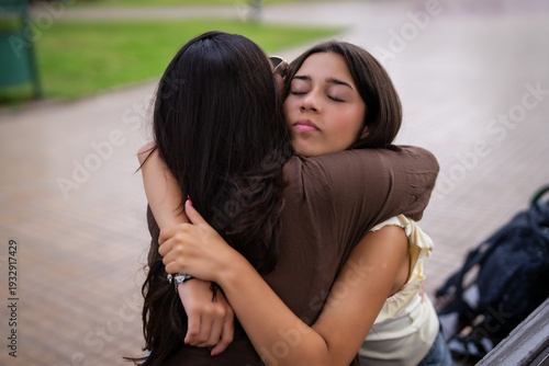 Foto Two young women hugging, comforting each other with closed eyes and affection