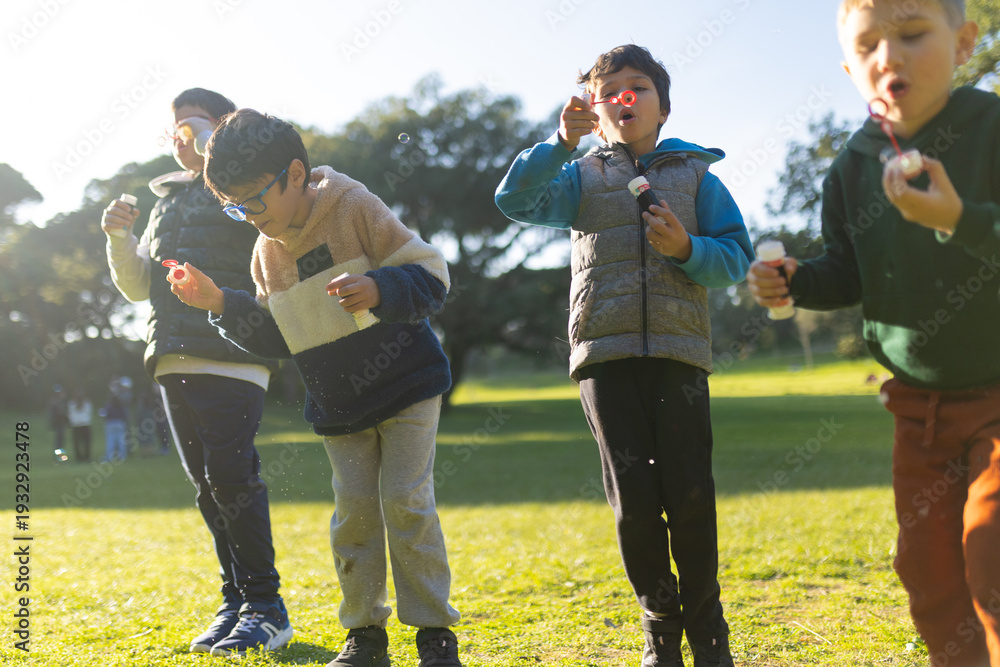 Fototapeta premium Young boys blowing bubbles having fun outdoors