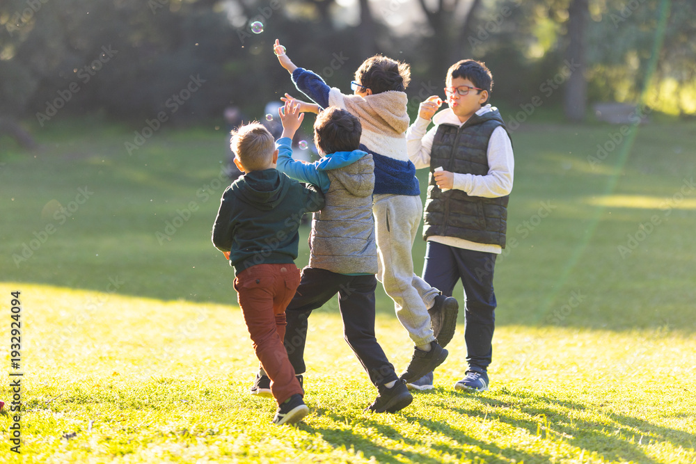 Fototapeta premium Boys playing with bubbles in a park
