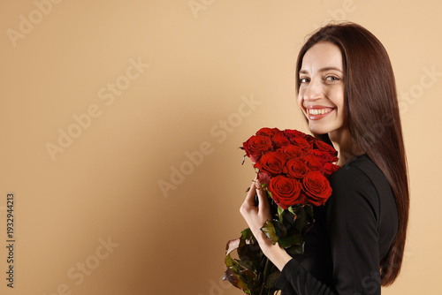 Woman with bouquet of red roses on beige background, space for text