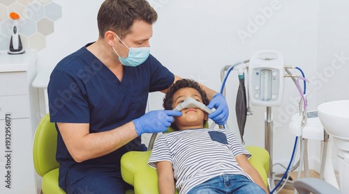 Male dentist in scrubs placing a nitrous oxide sedation mask on a calm little boy in a dental chair, pediatric dentistry, safe medical care, pain free treatment.