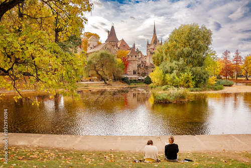 Autumn landscape in the park, two girls drawing by the lake
