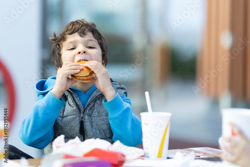 Young boy eating fast food hamburger meal