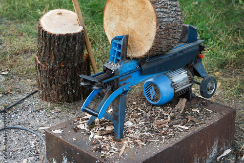 Cuadro en lienzo Electric log splitter machine splitting a large firewood log outdoors