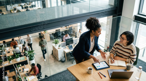 Two diverse businesswomen talking in an open office.
