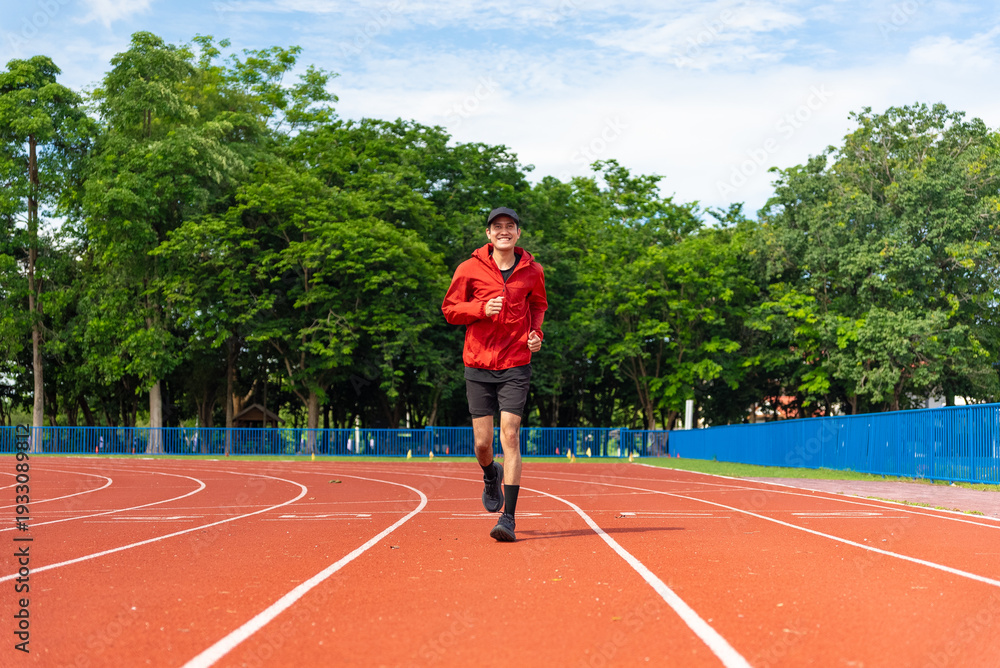 Fototapeta premium Young Asian men are exercising with outdoor running with a running track background in the morning. Concept healthy running and outdoor exercise, Tracking shot,
