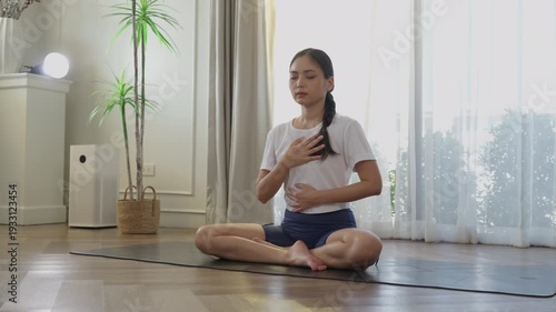 Asian woman yoga meditation lotus pose on mat at home, practicing breathing and concentration, wellness balance harmony for health