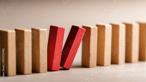 Domino Effect: Two red dominoes stand out from a line of wooden dominoes, embodying the concept of risk and the potential for a chain reaction in a clear, focused image.