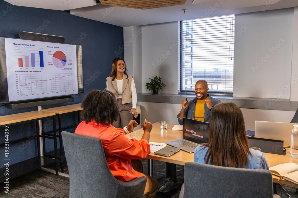 Fototapeta premium Diverse coworkers presenting and discussing charts on large monitor in conference room with laptops
