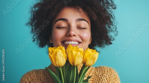 Woman Smiles While Holding Yellow Tulips Against a Blue Background in a Brigh...
