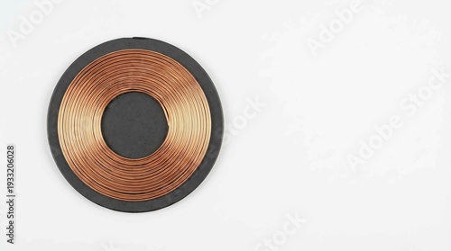 Close-up of a circular copper induction coil on a dark base, ready for wireless power transfer.