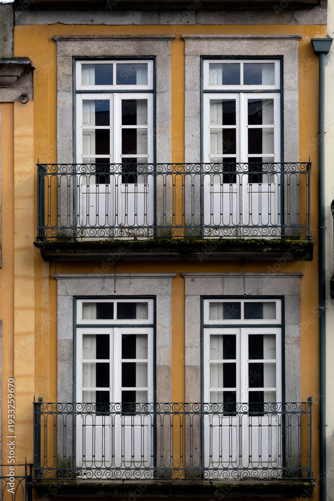 Obraz premium Symmetrical mustard building facade with balconies and white windows. 