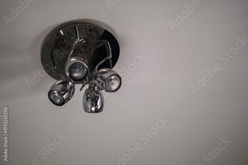 A minimalist ceiling-mounted spotlight fixture with multiple adjustable chrome lamps against a clean white ceiling