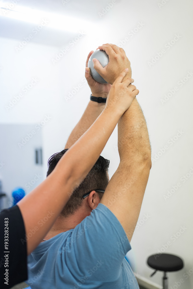 Fototapeta premium Therapist assisting man with rehabilitation ball exercise