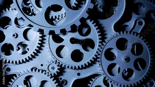 Close-up of intricate metallic gears interlocking and rotating in a dark industrial setting.