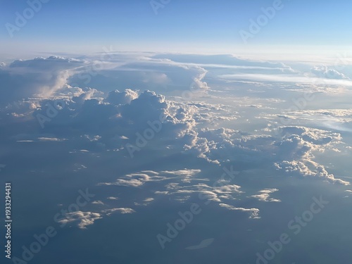 Aerial bird view from airplane of white and blue clouds, cloud scape, view from above, low sun casting shadows, blue skies, August, Northern Germany