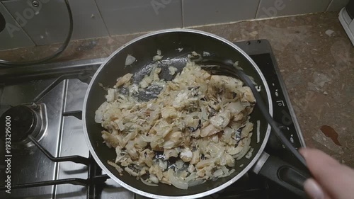 Cooking fish with onion on black frying pan