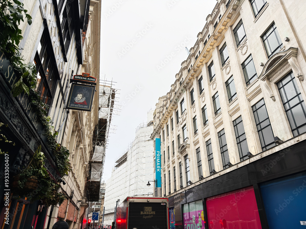 Fototapeta premium Busy Manchester street scene with construction, shops, and bright storefronts in the UK