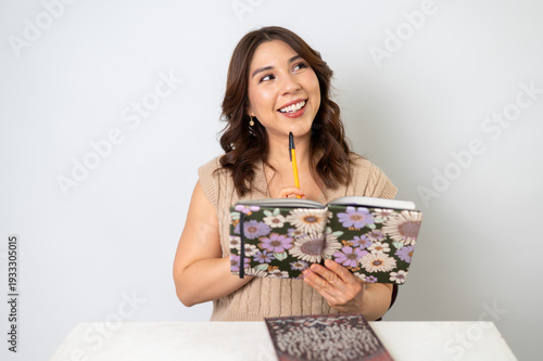 Mujer inspirada sosteniendo pluma y libreta pensando en una idea