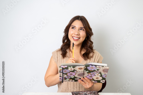Mujer inspirada sosteniendo pluma y libreta pensando en una idea