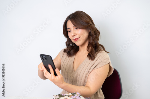Mujer profesional usando smartphone en oficina con fondo neutro