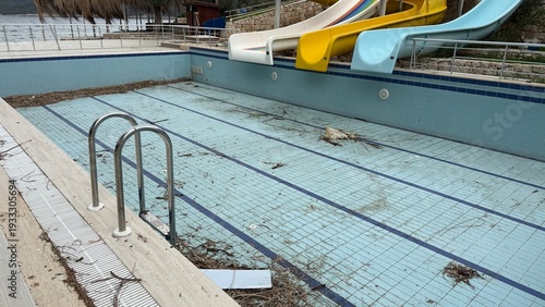 Empty swimming pool with debris in off-season outdoor area showing neglect and disuse
