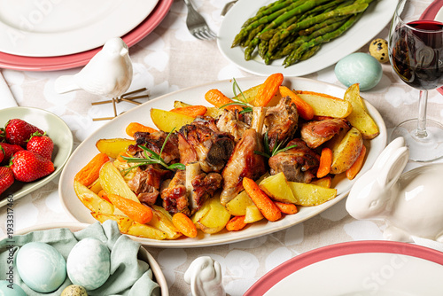 Homemade Easter dinner. Oval plate with Oven roasted Lamb with Carrots & Potatoes. Asparagus, colored easter eggs.  Strawberries, red wine.