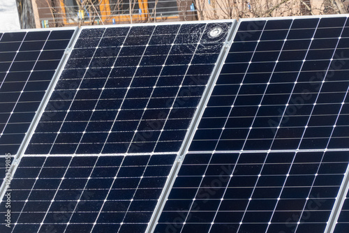 Cracked solar panel with visible impact damage on photovoltaic module installed outdoors. Broken glass surface on renewable energy system highlighting maintenance issues, energy loss