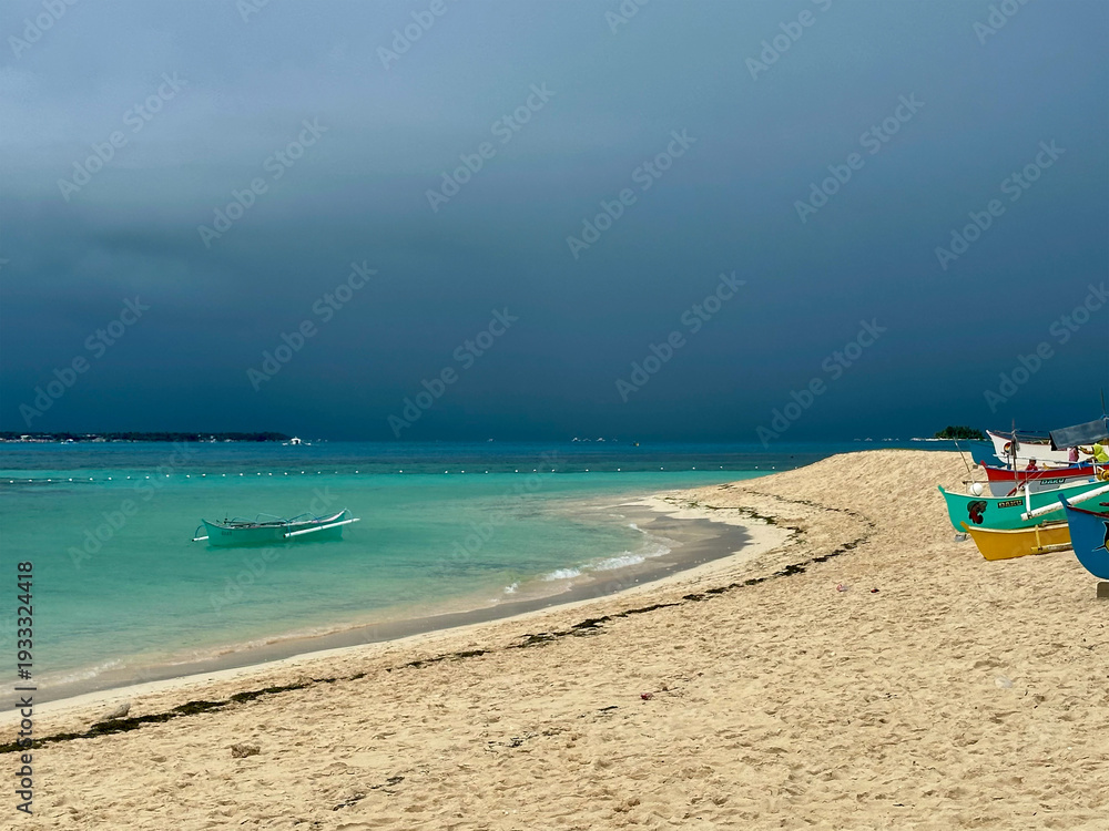 Obraz premium Storm over tropical sea with boats on island with turquoise waters, Guyam Island, Siargao, Philippines 