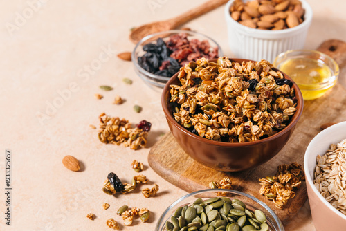 Obraz na plátně A flat lay view of a bowl with homemade crunchy granola clusters surrounded by raw ingredients like oats, nuts, seeds, and honey
